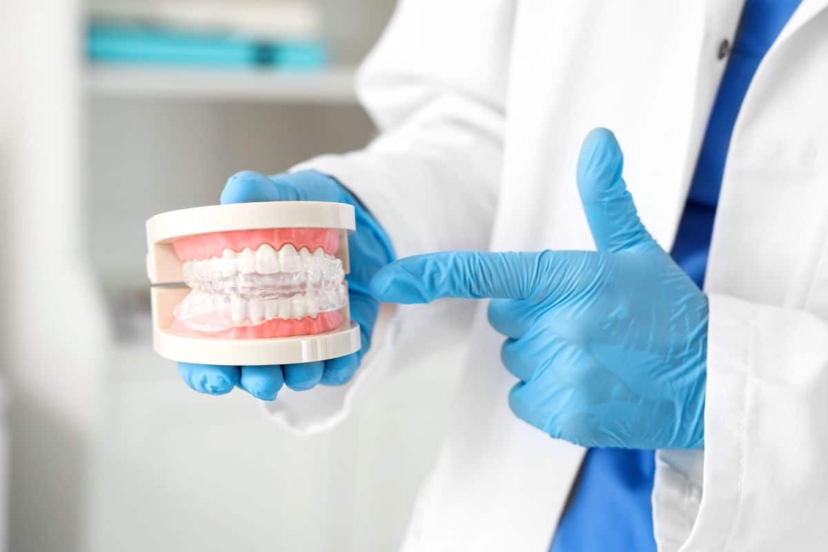 Dentista mostrando modelo dental y protector bucal.