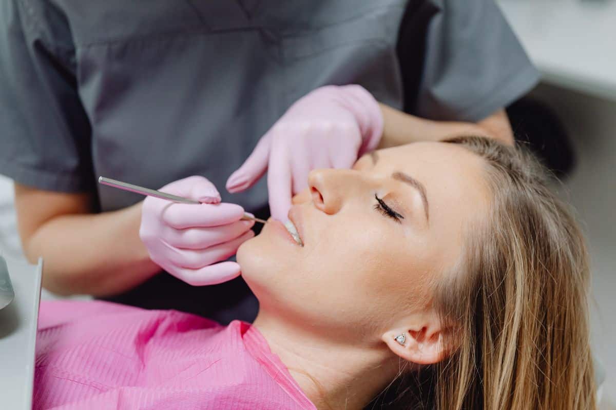 Dentista revisando dientes de paciente en consulta.
