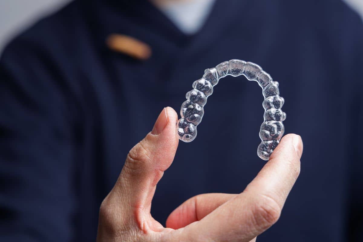 Mano sosteniendo alineador dental transparente